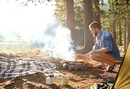 Man in a blue shirt starting a camp fire
