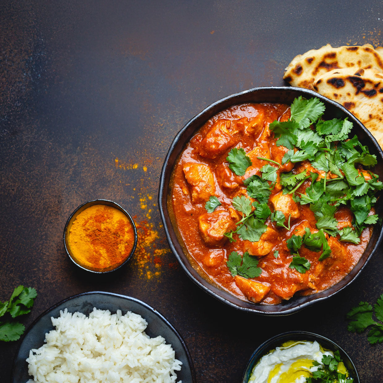 Chicken Tikka Masala with rice and naan on a dark background