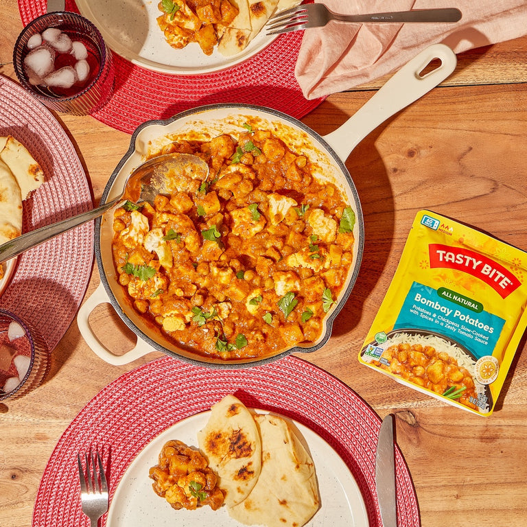 Tasty Bite Bombay Potatoes served in a skillet with naan bread and rice for a flavorful Indian meal
