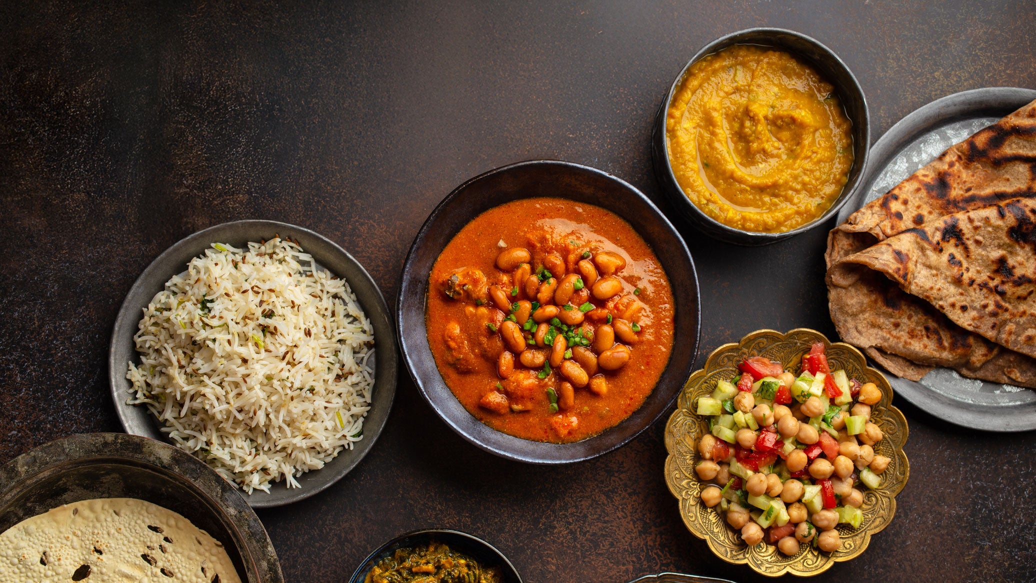 Indian vegetarian meal with rice, beans curry, lentil dal, roti, and chickpea salad