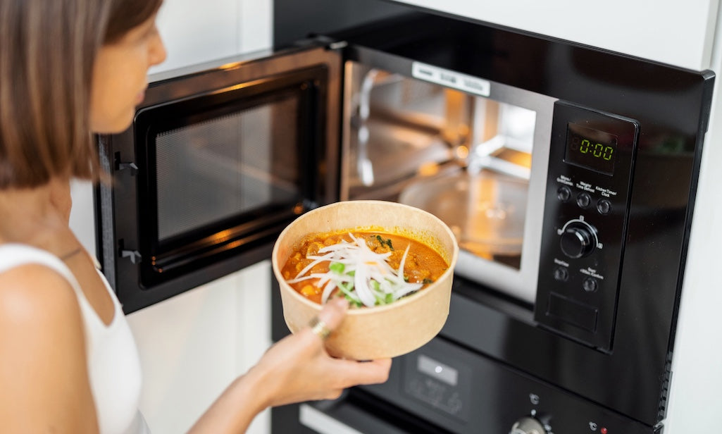 Woman heating a Tasty Bite meal in the microwave for a quick dinner.